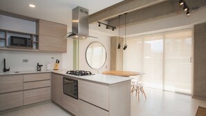 Une cuisine moderne dotée d’un îlot central, d’un four à micro-ondes encastré et d’une hotte en acier inoxydable.