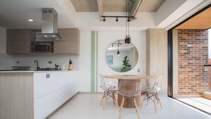 Une cuisine moderne dotée d’un îlot central, d’un coin repas avec une table ronde et des chaises, et d’un grand miroir au mur.