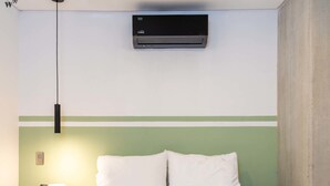 A hotel room with a bed, a bedside table, a lamp, and an air conditioning unit on the wall. - w Beautiful 3BR w/ AC in Laureles (Medellín)