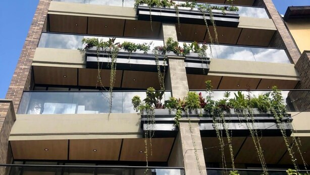 A multi-story building with balconies, each featuring planters with greenery. - Jungle Style 1BR in Laureles (Medellín)
