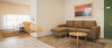 A modern living room with a sectional sofa, a wicker chair, and a small coffee table.