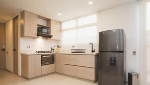 A modern kitchen with a built-in oven, microwave, and stainless steel refrigerator. - Jungle Style 1BR in Laureles (Medellín)