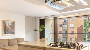 Une cuisine moderne dotée d’un four encastré, d’une cuisinière à gaz et d’une grande fenêtre donnant sur un quartier résidentiel.