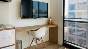 A modern kitchen with a wooden countertop, a white chair, a stainless steel trash bin, and a flat-screen TV mounted on the wall. - w Loft in Chapinero (Bogotá)