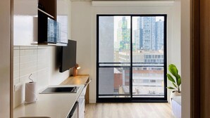 A modern kitchen with a built-in oven, a flat-screen TV, and a large window with a city view. - w Loft in Chapinero (Bogotá)