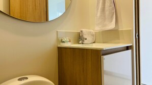 A bathroom with a toilet, a sink with a mirror above it, and a towel hanging on a rack. - w Loft in Chapinero (Bogotá)