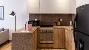 Una cocina compacta con encimera de granito, electrodomésticos de acero inoxidable y armarios de madera.