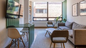 Una sala de estar moderna con televisión, zona de estar y ventanas amplias.