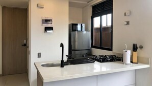A modern kitchen with a white countertop, stainless steel appliances, and a window with blinds. - Splendid Loft With Terrace in Laureles (Medellín)