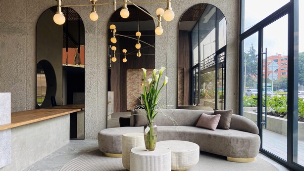 A modern lobby with a large seating area, a reception desk, and a view of the city through large windows. - w Artistic Loft in Unique Building (Bogotá)