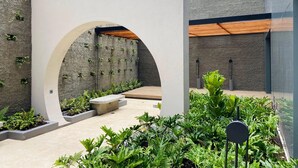 A modern outdoor area with a concrete archway, a wall with vertical planters, and a variety of greenery. - w Artistic Loft in Unique Building (Bogotá)