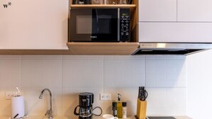 Une cuisine moderne équipée d’un four à micro-ondes encastré, d’une machine à café et d’une tablette posée sur le plan de travail.