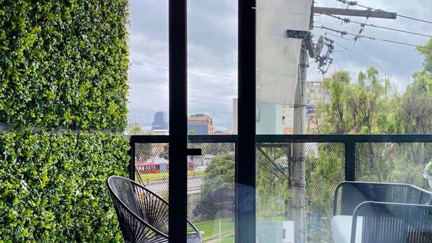 A balcony with a view of the city, a bed with white linens, and a black chair. - w Astounding Loft in Virrey (Bogotá)