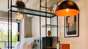 A modern hotel room with a bed, a round wooden table, a chair, a pendant light, and a shelf with decorative items. - w Astounding Loft in Virrey (Bogotá)