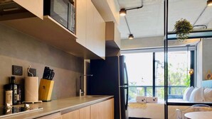 A modern kitchen with wooden cabinets, a black refrigerator, and a dining area with a round table and chairs. - w Astounding Loft in Virrey (Bogotá)