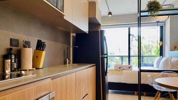 Una cocina moderna con armarios de madera, un refrigerador negro y una zona de comedor con una mesa redonda y sillas.