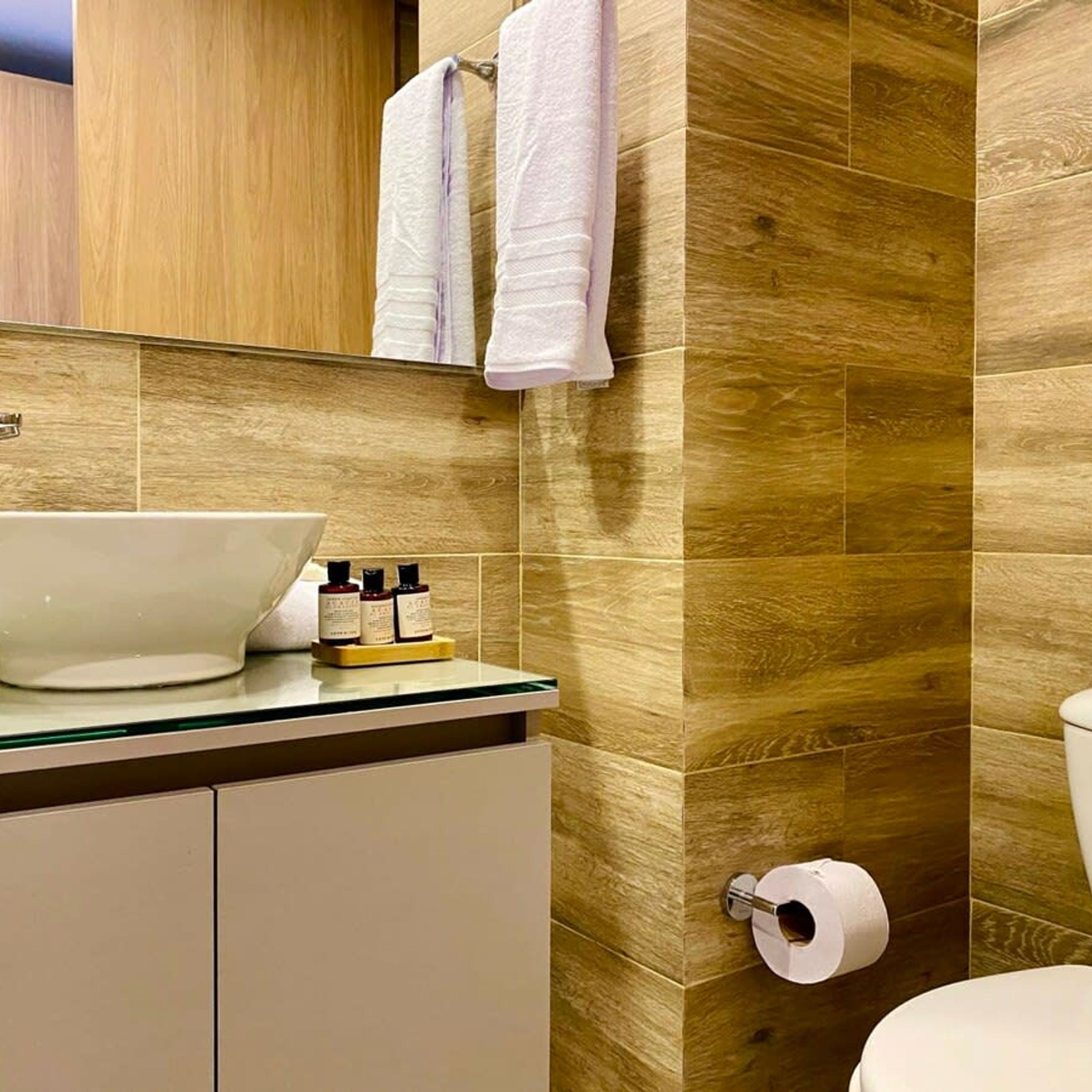 A bathroom with a wooden wall, a white sink, and a toilet.