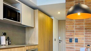 A modern kitchen with wooden cabinets, a built-in oven, a microwave, and a round island with a pendant light. - w Lovely Loft in Virrey (Bogotá)