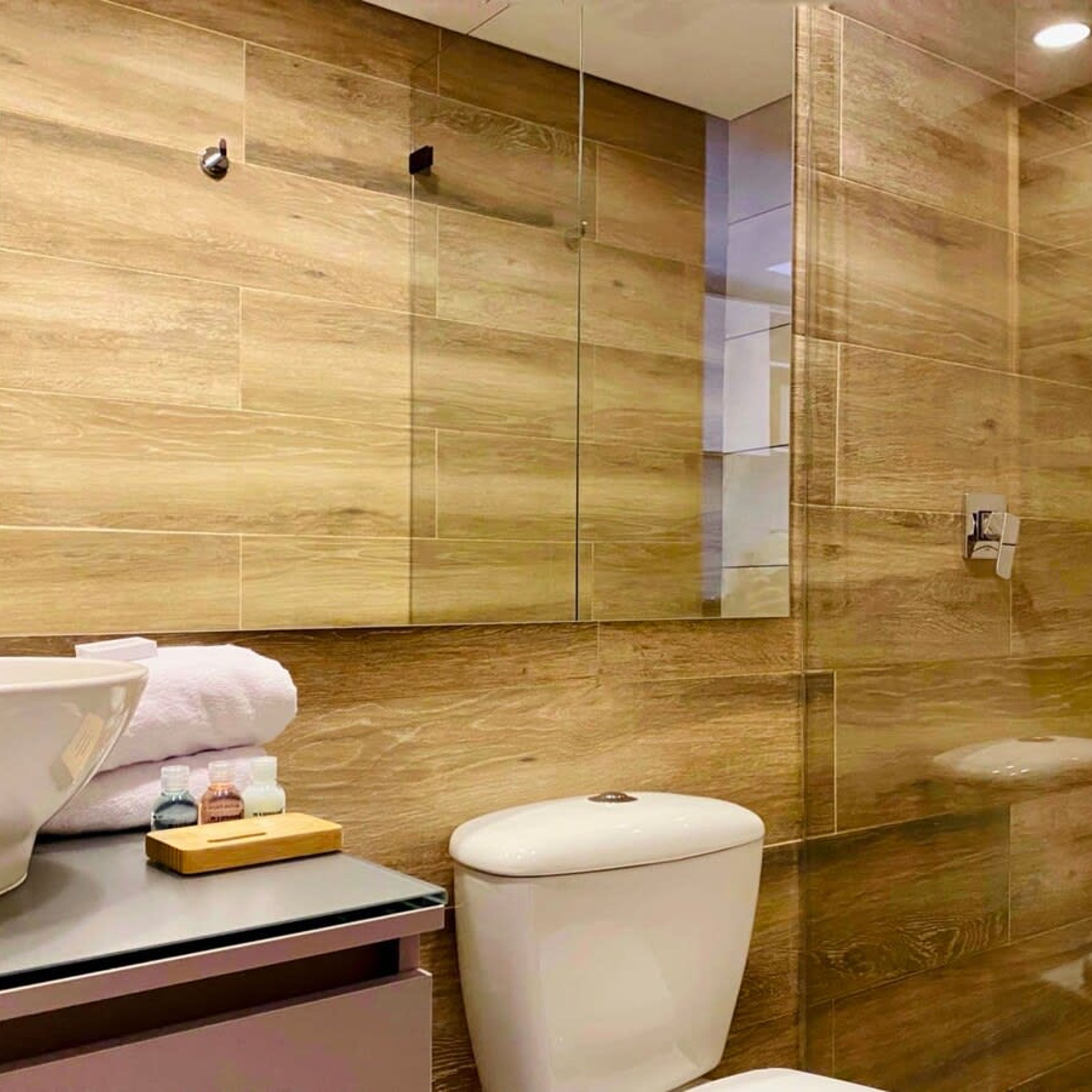Ein modernes Badezimmer mit einer Holzvertäfelung, einem weißen Waschbecken und einer Toilette.
