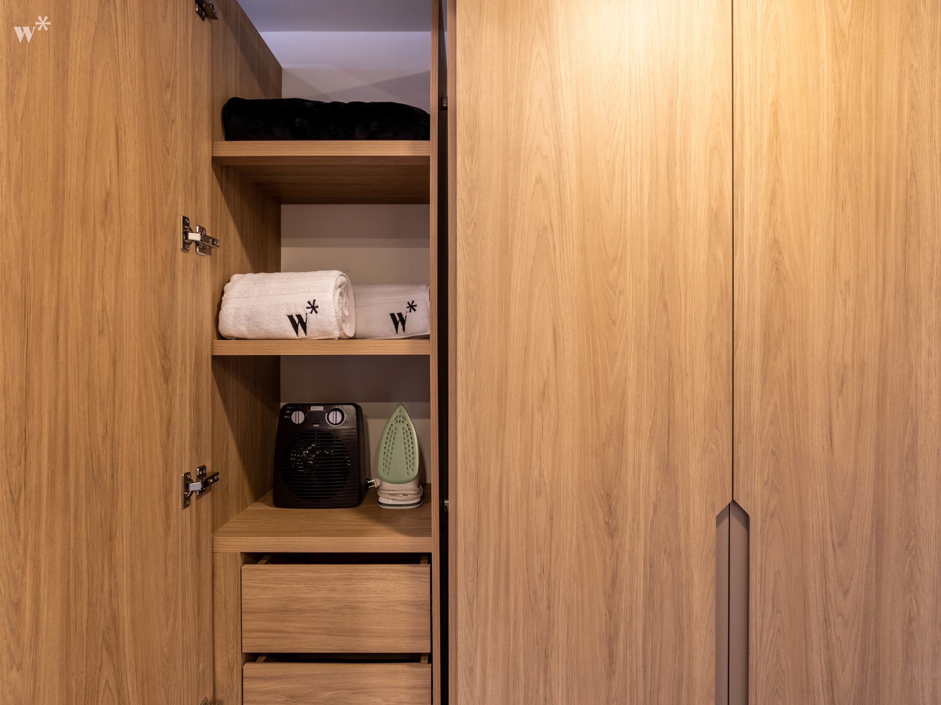 Un armario de madera con dos repisas, espacio para colgar y un cajón.