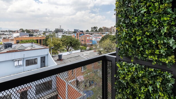 A balcony with a view of a cityscape, including buildings and a cloudy sky.