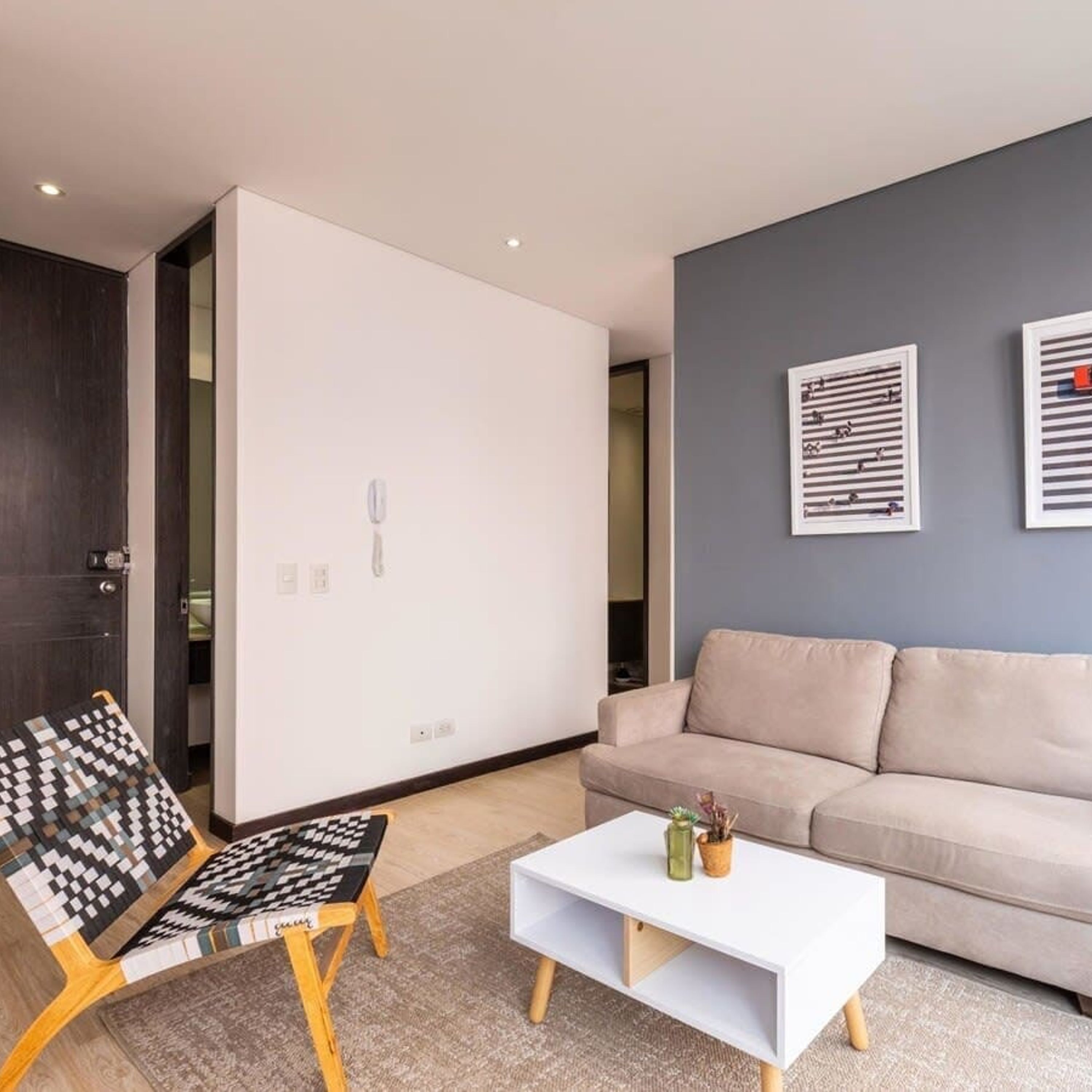 Ein modernes Wohnzimmer mit einer Couch, einem Couchtisch und einem gemusterten Sessel.