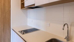 A kitchen with white cabinets, a stainless steel sink, and a built-in range hood. - w Modern Loft in Chapinero (Bogotá)