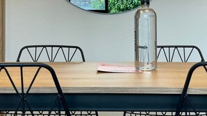A dining area with a round mirror, two pendant lights, a bottle, and a table with chairs. - w Extraordinary 2BR in Laureles (Medellín)