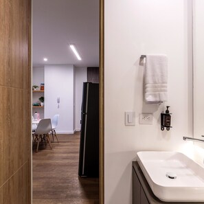 A modern bathroom with a white sink, a towel hanging on the wall, and a black cabinet. - w Captivating 2BR in Parque Virrey (Bogotá)