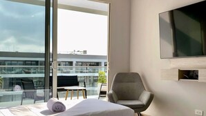 Une chambre d’hôtel avec deux lits, une télévision et un balcon donnant sur des immeubles.