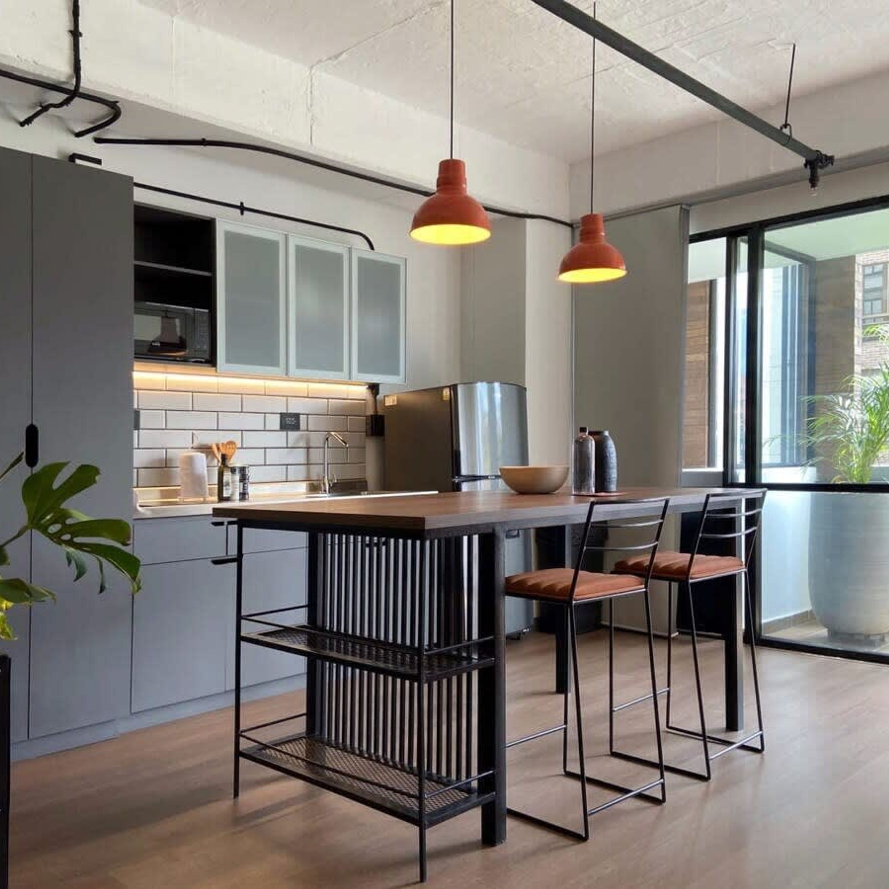 Una cocina moderna con armarios grises, una isla de madera y dos lámparas colgantes.