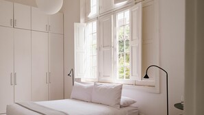 A bedroom with a bed, white wardrobe, and a window with open shutters. - w Astonishing Casa Centenario in Barranco (Lima)