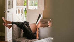 A person lying on a couch reading a book with a window view. - w Astonishing Casa Centenario in Barranco (Lima)