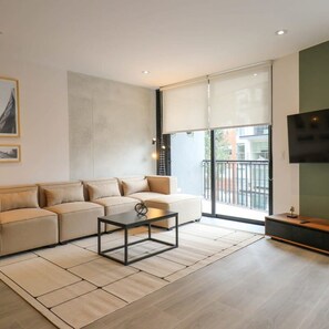 A modern living room with a sectional sofa, a coffee table, and a flat-screen TV. - w Unique 2BR With Balcony in Miraflores (Lima)