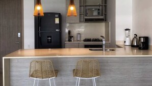 A modern kitchen with a central island, two pendant lights, a refrigerator, a microwave, a stove, and two bar stools. - w Fantastic 2BR w AC in Sunny Cartagena (Cartagena)
