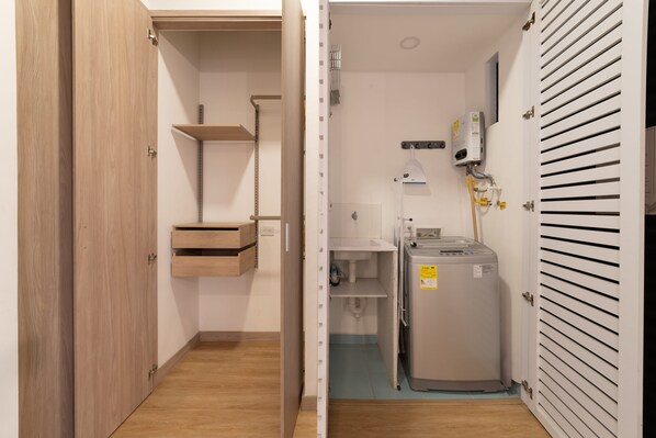 A compact bathroom with a toilet, sink, and a compact heater unit.