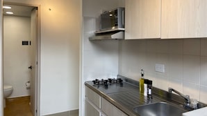 A modern kitchen with a stainless steel sink, a gas stove, and a microwave. - w Modern 1BR With Terrace at Poblado (Medellín)
