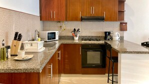 A modern kitchen with wooden cabinets, a microwave, a stove, and a dishwasher. - w Oceanview 2BR w/ Terrace n AC in El Laguito (Cartagena)