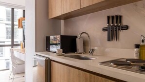 Una cocina moderna con armarios de madera, microondas integrado, un lavabo y una cafetera.