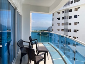 A balcony with a glass railing, two chairs, and a table. - w Lovely 2BR w Beautiful Ocean View n AC in CTG (Cartagena)