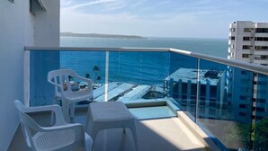 A balcony with a glass railing overlooking a coastal view, featuring a small table and two chairs. - w Lovely 2BR w Beautiful Ocean View n AC in CTG (Cartagena)