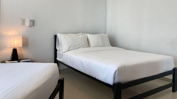 A single bed with white bedding in a room with white walls and a nightstand with a lamp. - w Lovely 2BR w Beautiful Ocean View n AC in CTG (Cartagena)