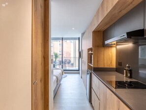 A narrow hallway leading to a balcony with a bed and a dining area. - Charming Loft in El Nogal (Bogotá)