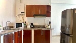 Een moderne keuken met houten kastjes, een roestvrijstalen koelkast, een magnetron, een koffiezetapparaat en een gasfornuis.