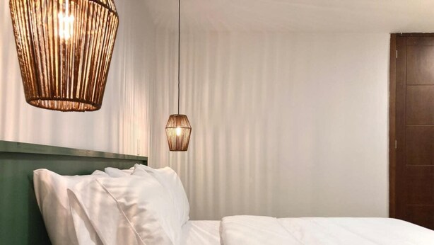 A neatly made bed with white linens, a green headboard, and two hanging light fixtures. - w Spectacular 2BR Apartment w/ AC in Cartagena (Cartagena)