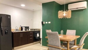 A modern kitchen with dark cabinets, a black refrigerator, and a dining area with a wooden table and four grey chairs. - w Spectacular 2BR Apartment w/ AC in Cartagena (Cartagena)