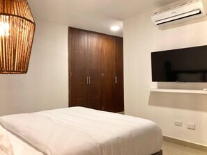 A bedroom with a bed, a wardrobe, an air conditioner, and a mounted TV. - w Spectacular 2BR Apartment w/ AC in Cartagena (Cartagena)