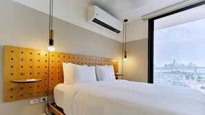 Une chambre d’hôtel moderne avec une tête de lit en bois, un grand lit et une vue sur la ville par une grande fenêtre.