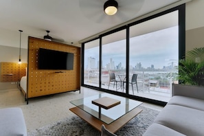 A modern living room with a large TV, a glass coffee table, and a sofa. - w Refined 1BR in Casco Antiguo (Panama City)