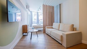 A modern living room with a sofa, a coffee table, and a flat-screen TV mounted on the wall. - Amazing Loft in Casco Viejo (Panama City)